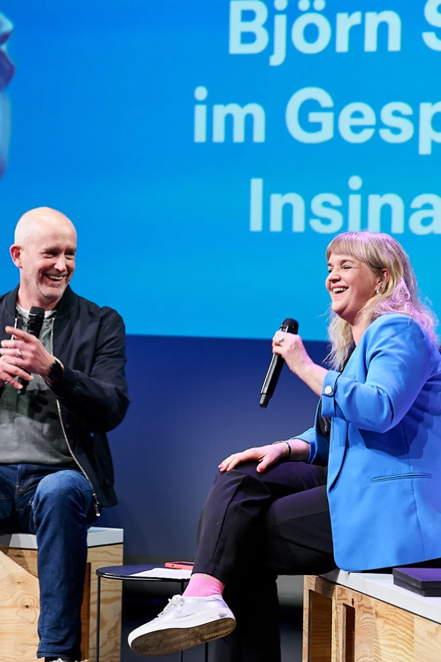 Zwei Personen mit Mikrofonen im Gespr&auml;ch auf der B&uuml;hne beim Tech For Society Slam.